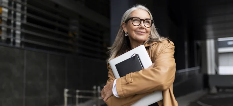 portrait of an elderly businesswoman with a laptop in glasses outside the office, strong and independent woman